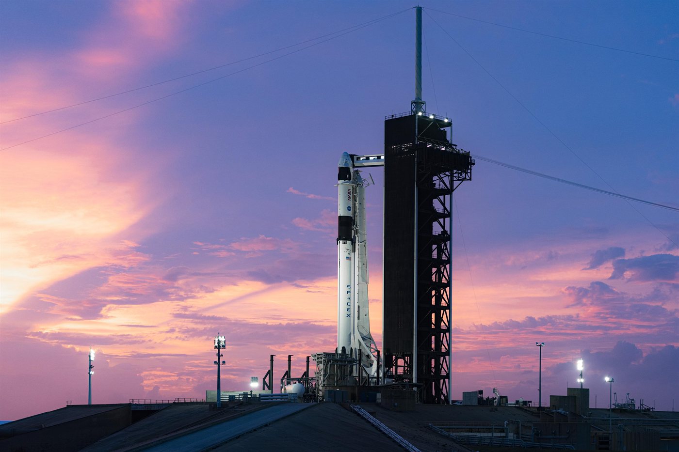 Falcon 9 with Dragon vertical on the launch pad at dusk